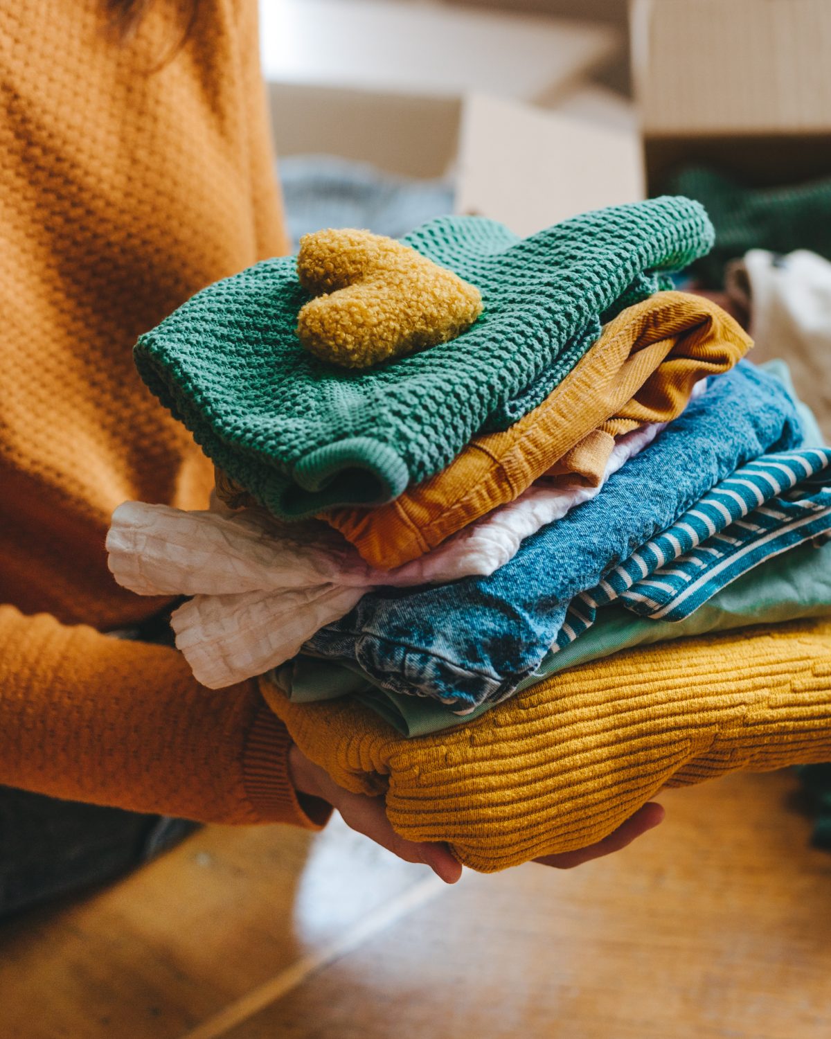A volunteer carrying a stack of freshly folded clothing