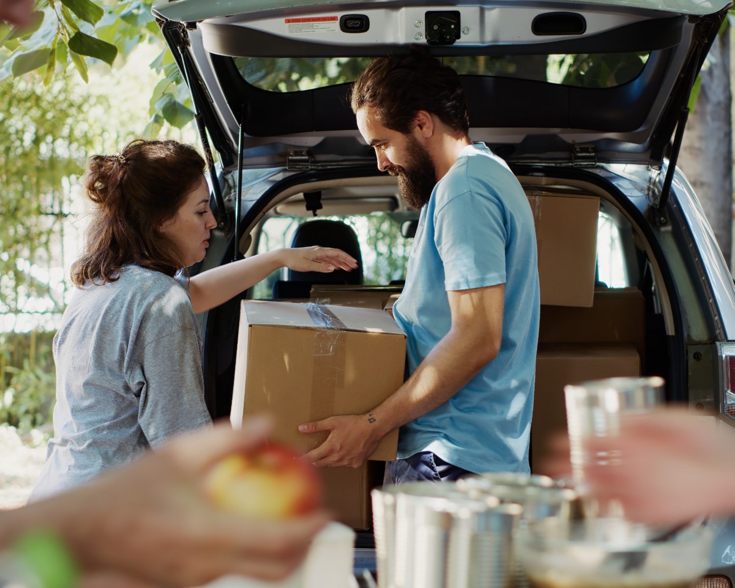 Two people loading boxes of food donations into the back of a car