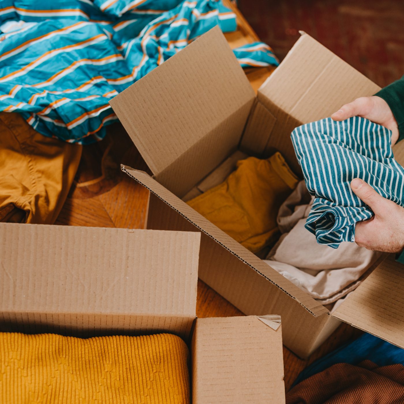 A volunteer folding a striped shirt into a cardboard box of sorted clothing